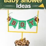 Football baby shower centerpiece with DIY goal post, “boy” banner, peanuts in bucket, and red baby shoes for themed party decor