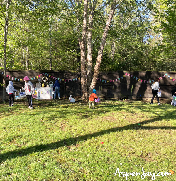 kids playing in backyard after Easter egg hunt with baskets and colorful eggs on grass