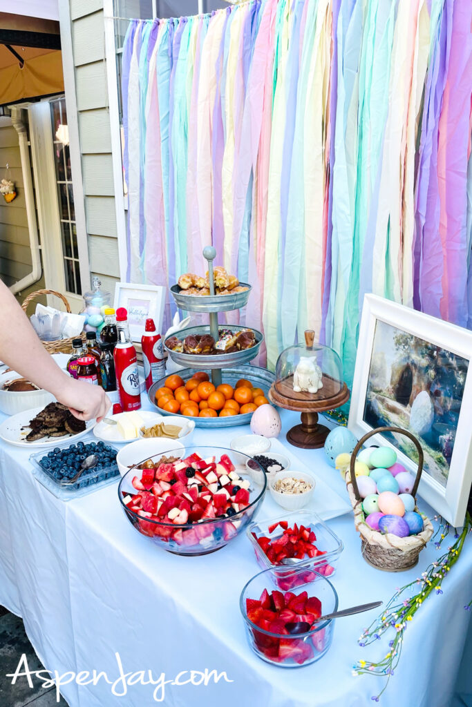 backyard Easter breakfast table with fruit, pancakes, and pastel decorations