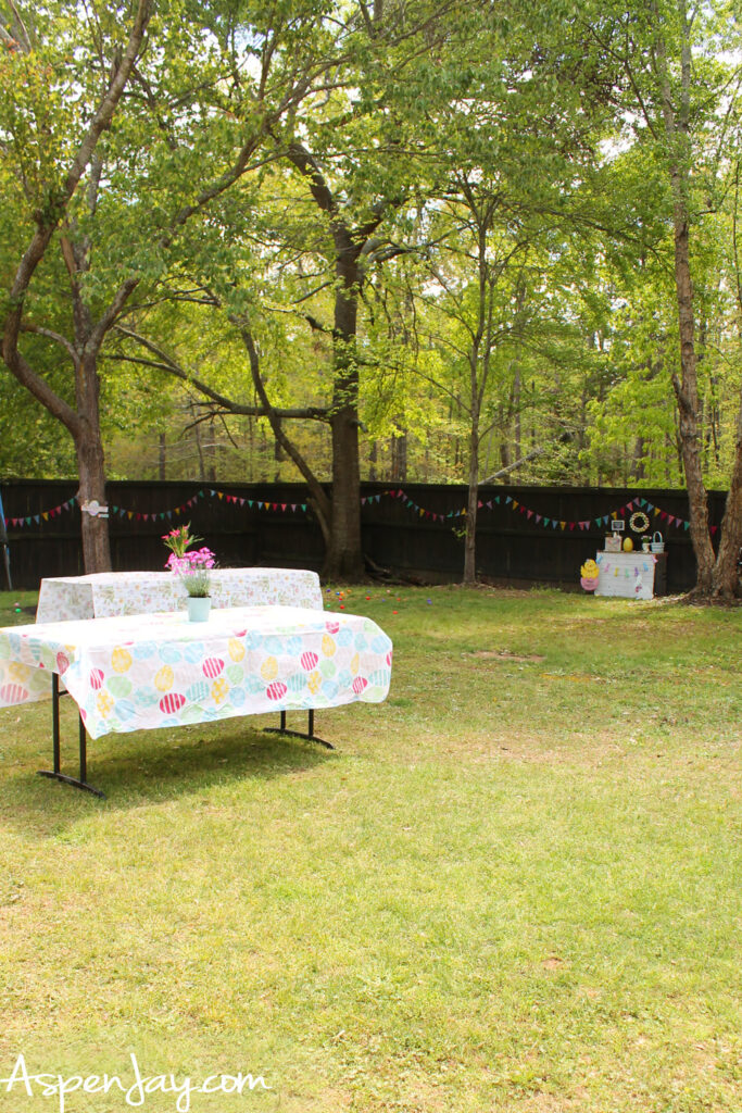 Backyard Easter party setup with decorated tables and egg hunt area