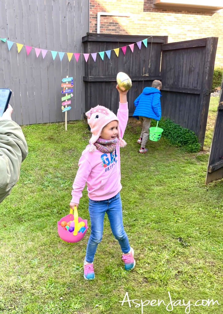 Golden egg Easter egg hunt winner holding a large golden egg in backyard
