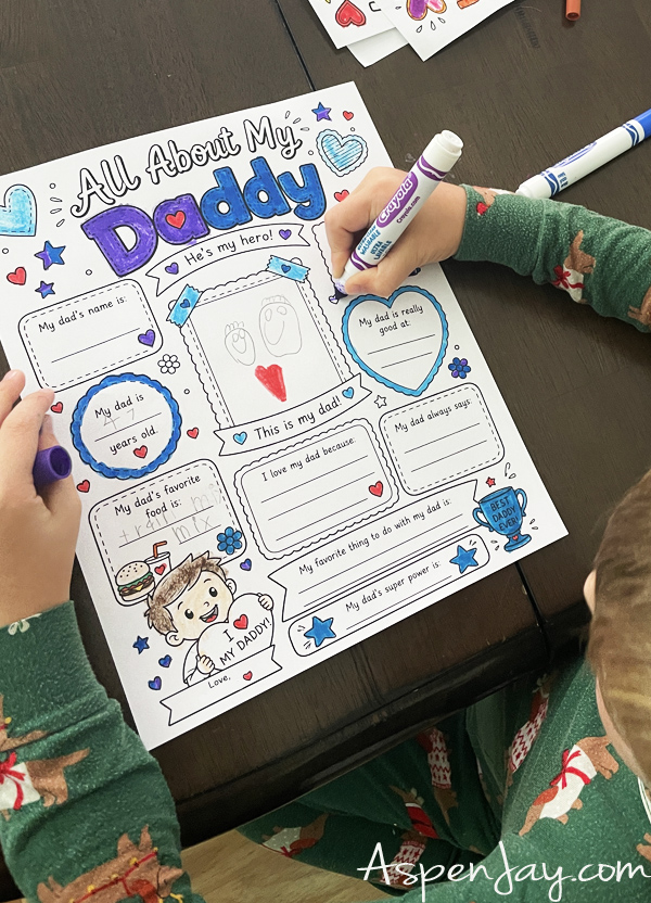 Little boy coloring an All About My Dad Father's Day printable questionnaire for kids.