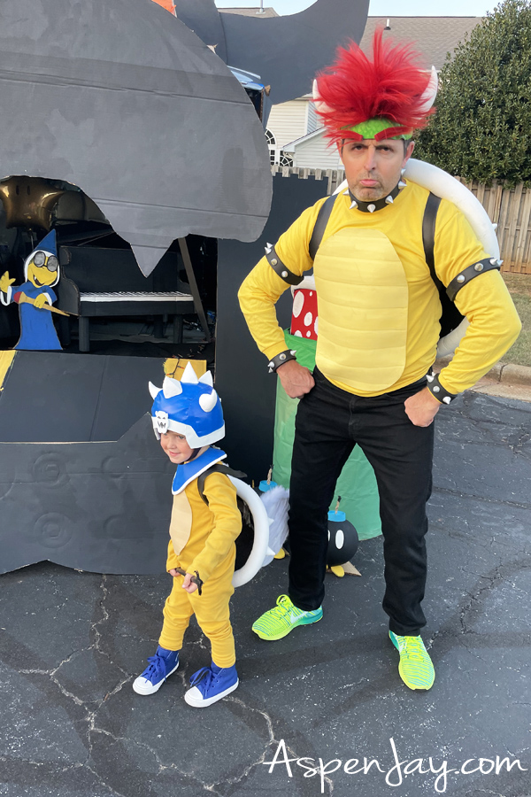 Koopa General Costume with Bowser costume in front of Bowser's castle trunk-or-treat display