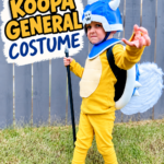 Child wearing a handmade Koopa General costume with a blue shell, helmet, yellow outfit, and blue shoes