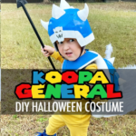 Child wearing a handmade Koopa General costume with a blue shell, helmet, yellow outfit, and blue shoes